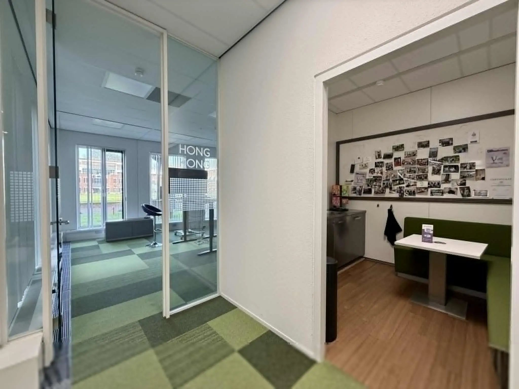 Kantoorinterieur aan de Arnhemse Bovenweg met een glazen vergaderruimte genaamd "Hong Kong" en een gezellige zithoek met fotowand.